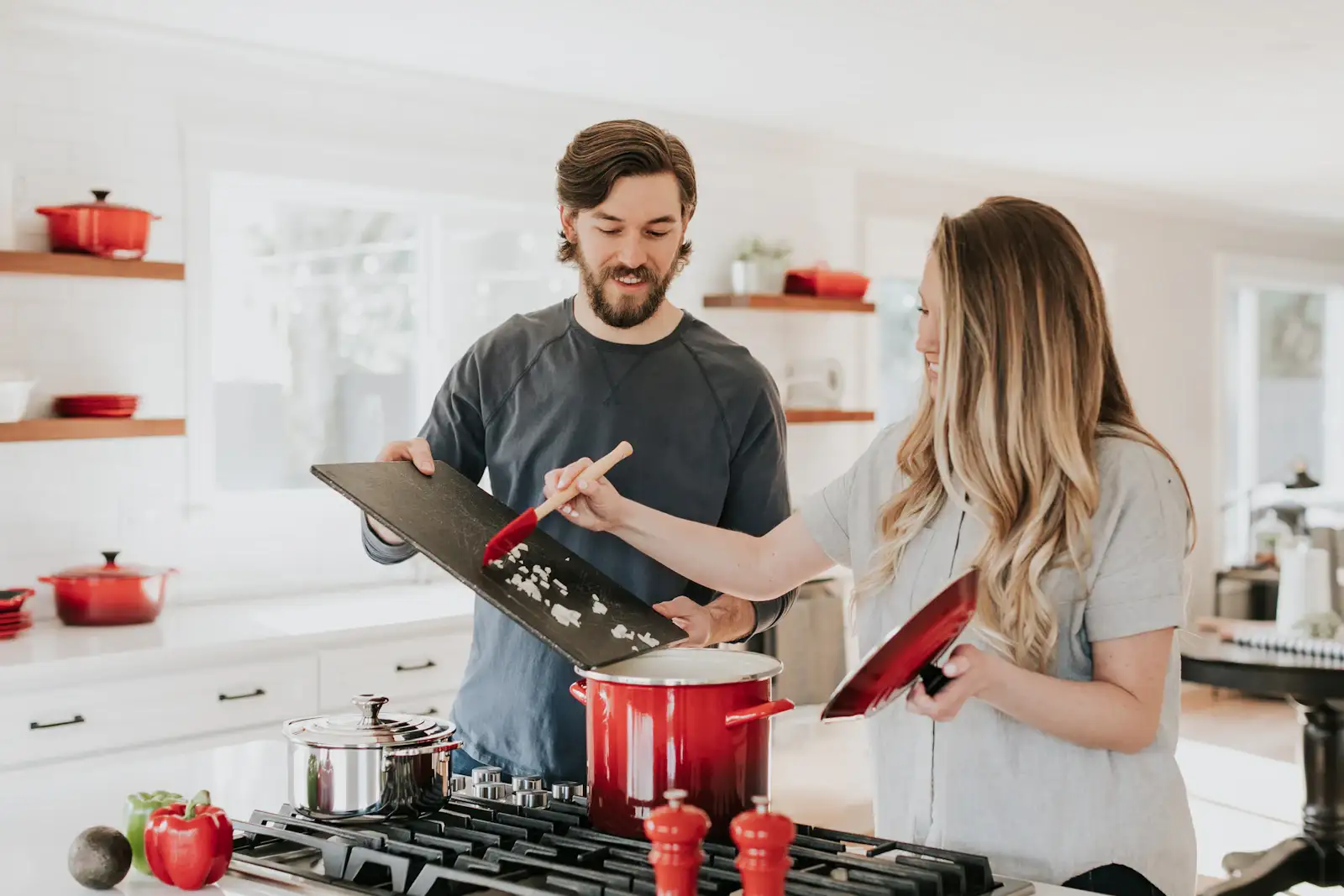 Two people cooking at a gas range in a white kitchen. Shown on the Kitchen refresh page for St. Petersburg, FL.