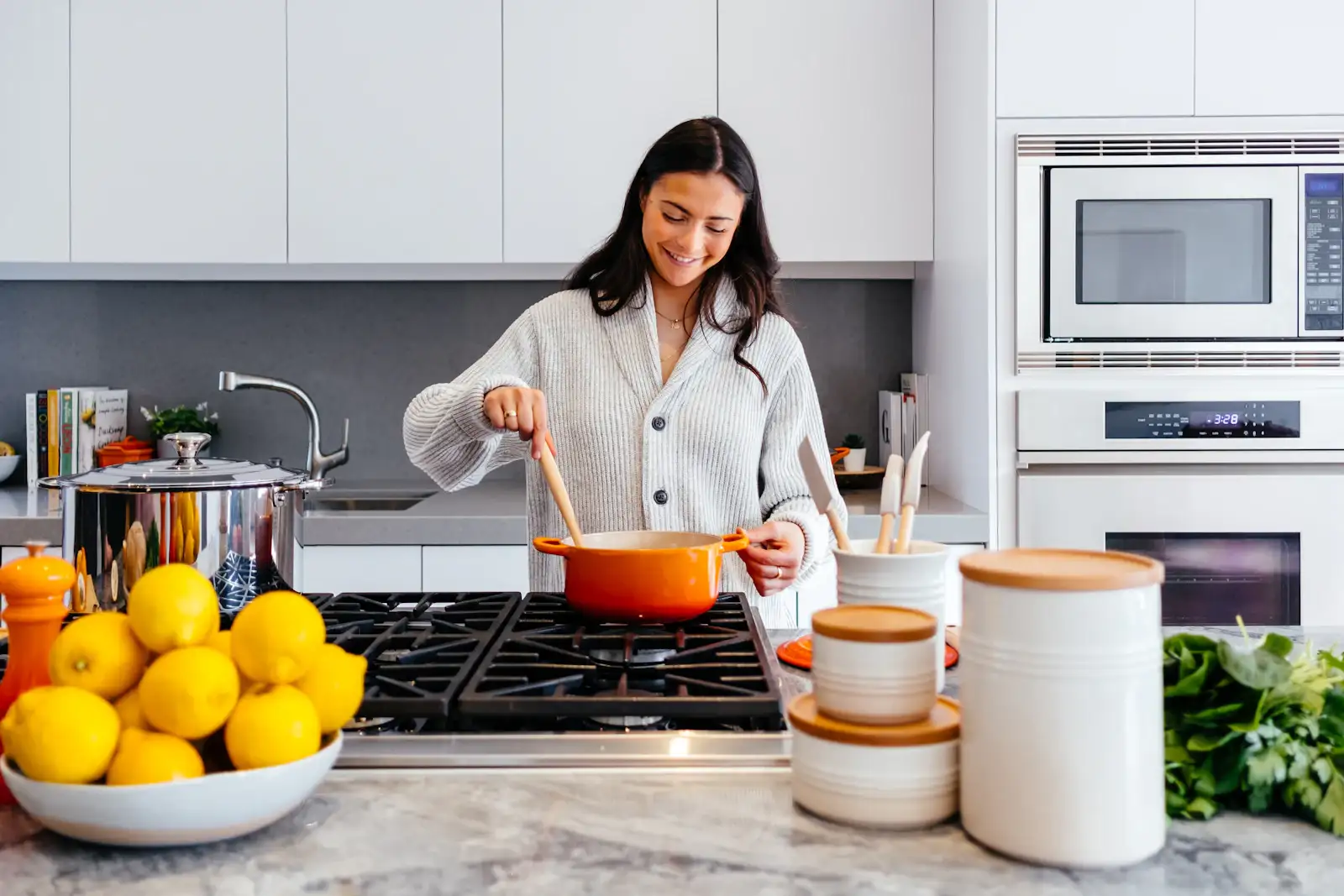 A cook at a gas range in a white kitchen with marble counters. Shown on the Task lighting page for St. Petersburg, FL.